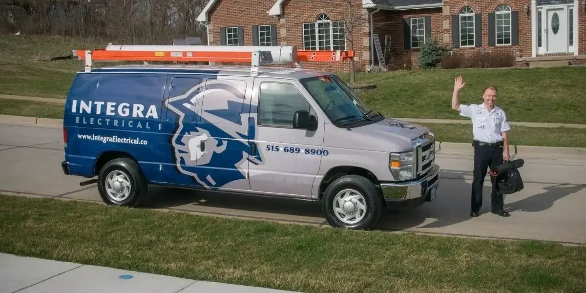 Integra Electrical service van parked outside a home with an electrician waving, ready to assist with residential electrical repairs in Des Moines.
