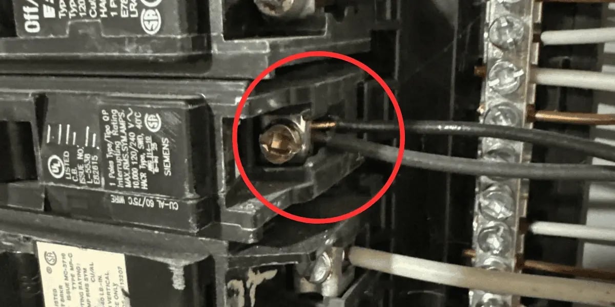 Close-up photo of an electrical panel showing a double tapped breaker with two wires connected to one terminal, which can cause overheating and needs professional repair.
