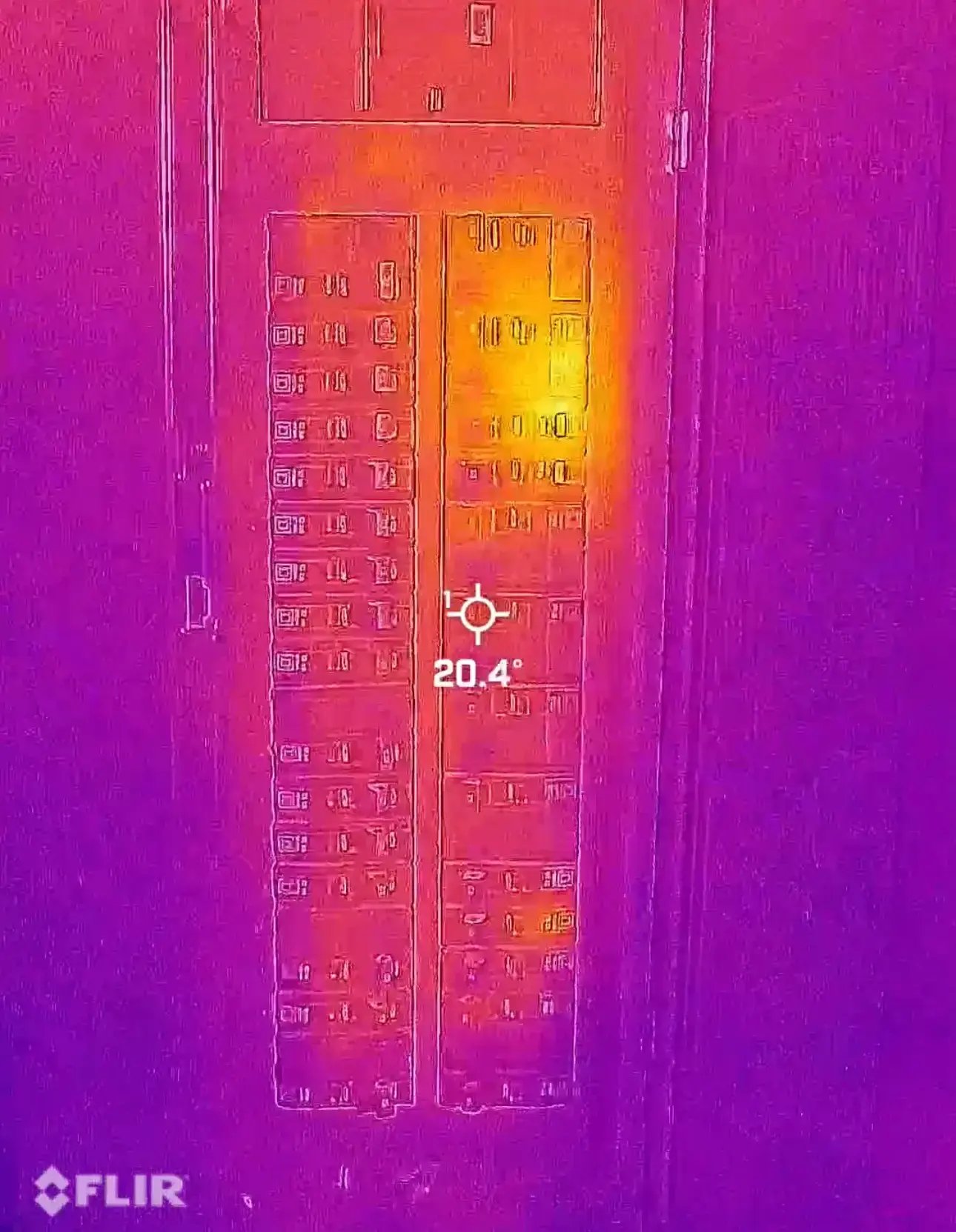 Thermal camera image of an electrical breaker panel showing heat buildup on one circuit, indicating potential overload or faulty connection.