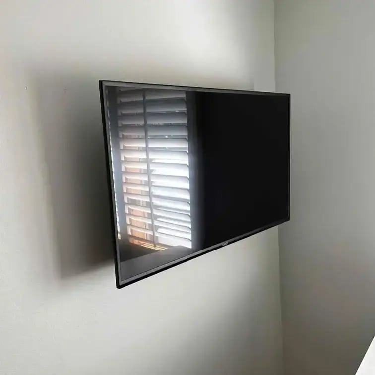 A tv mounted on a white wall near a corner