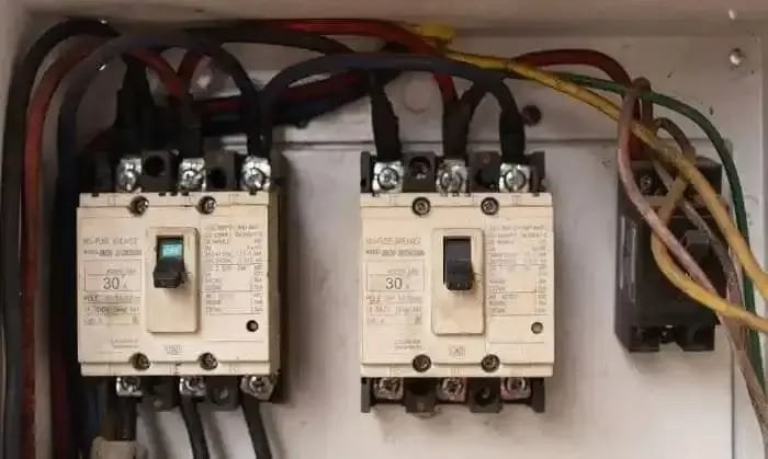 Close-up view of electrical breakers with visible wiring inside a panel.