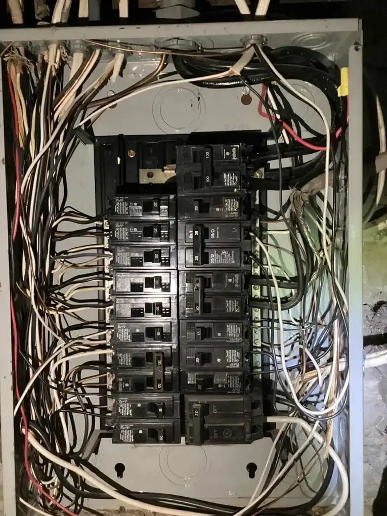Open electrical panel showing multiple breakers and wiring connections.