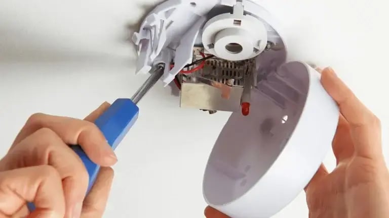 Electrician using a screwdriver to install a smoke detector