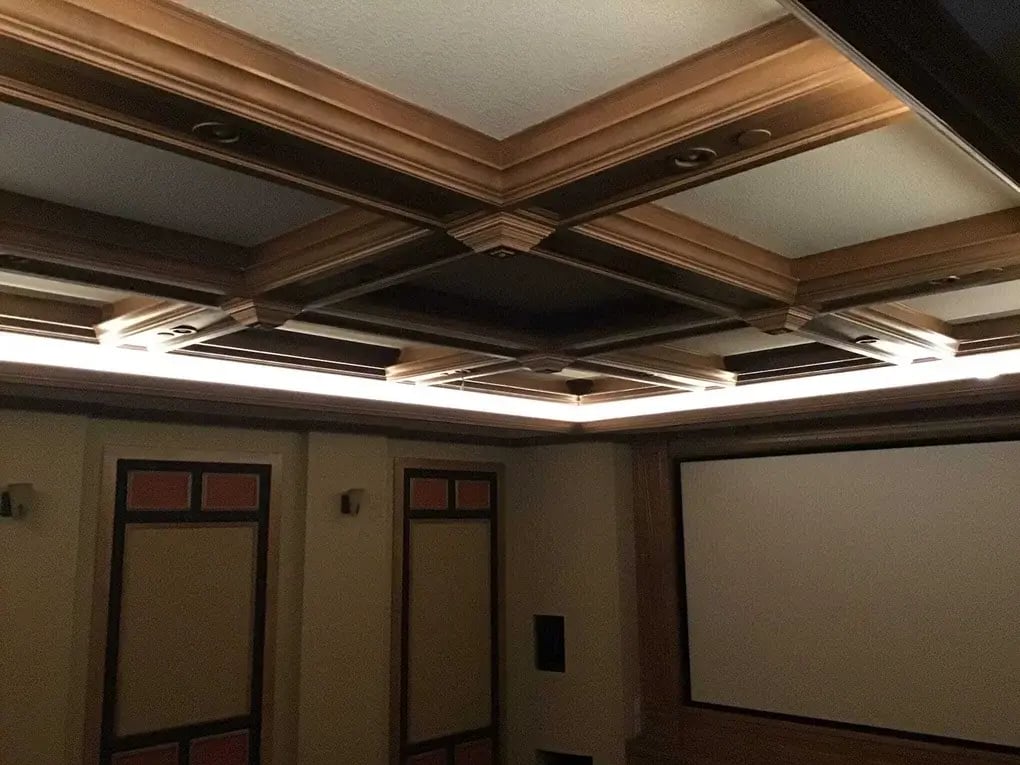 Home theater room with recessed lighting installed in a coffered ceiling above a projection screen.