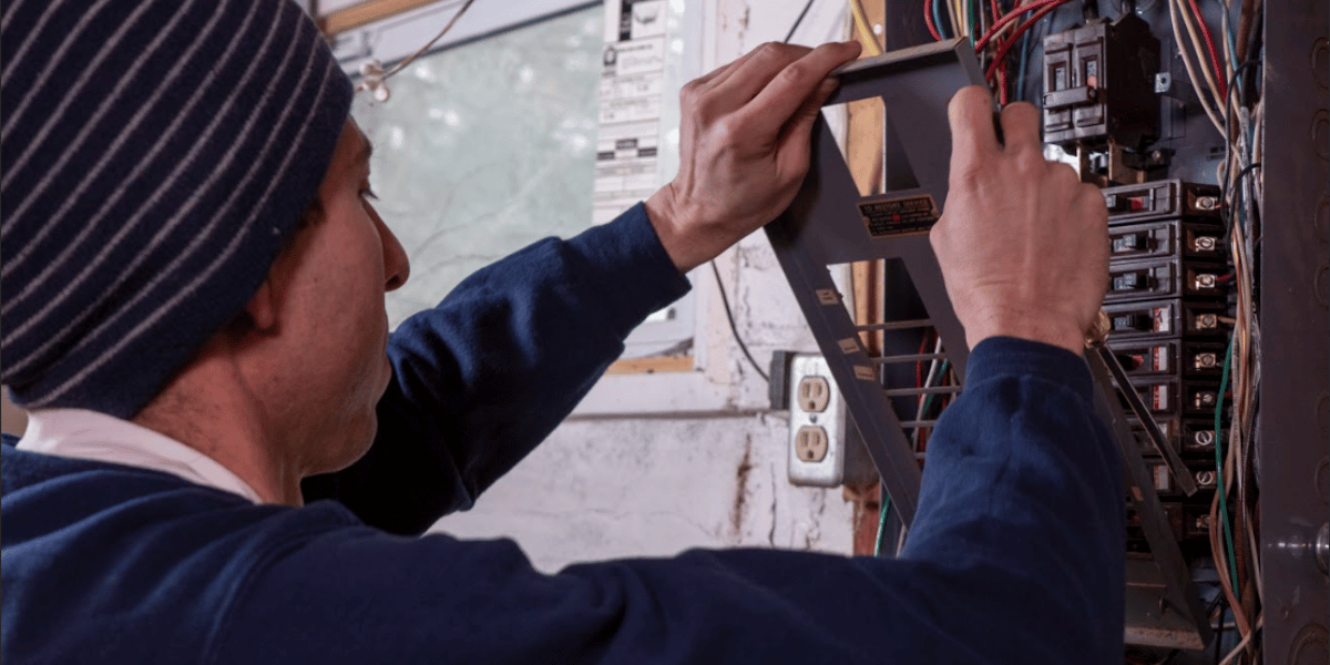 Electrician taking cover off of an electrical panel