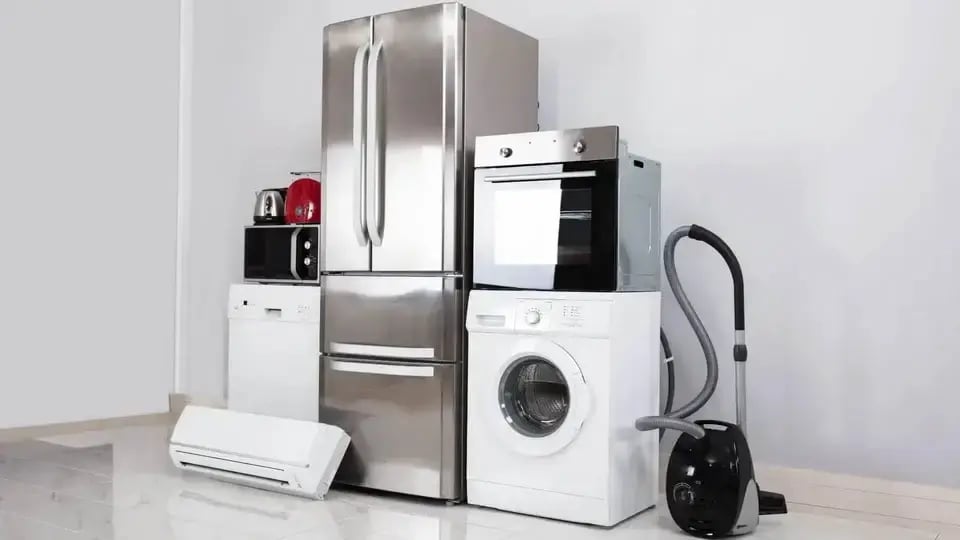 Modern home appliances including refrigerator, washing machine, oven, dishwasher, and vacuum cleaner arranged in a kitchen.