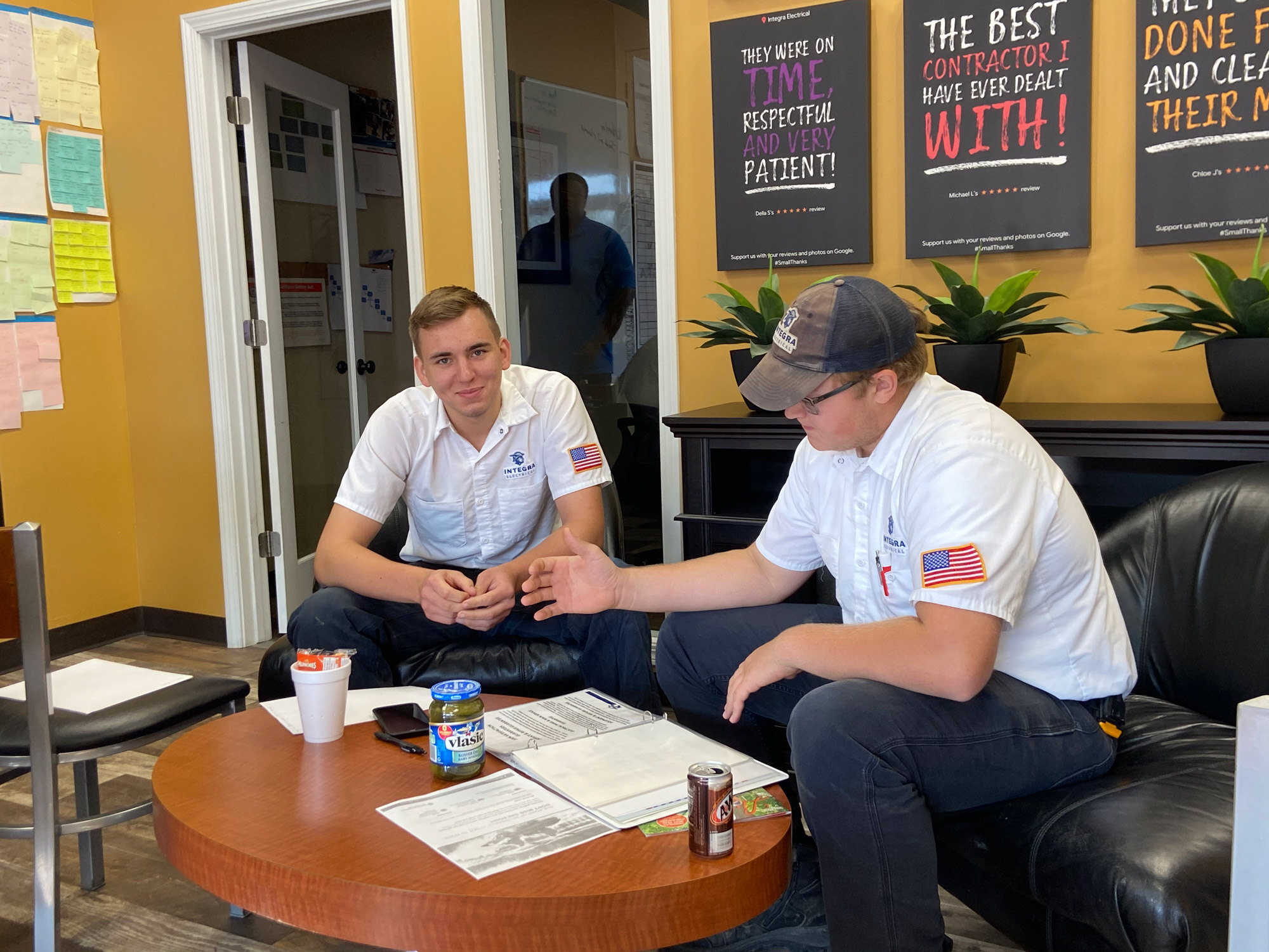 Two Integra Electrical team members sit together in the office, reviewing paperwork and having a focused discussion around a coffee table.
